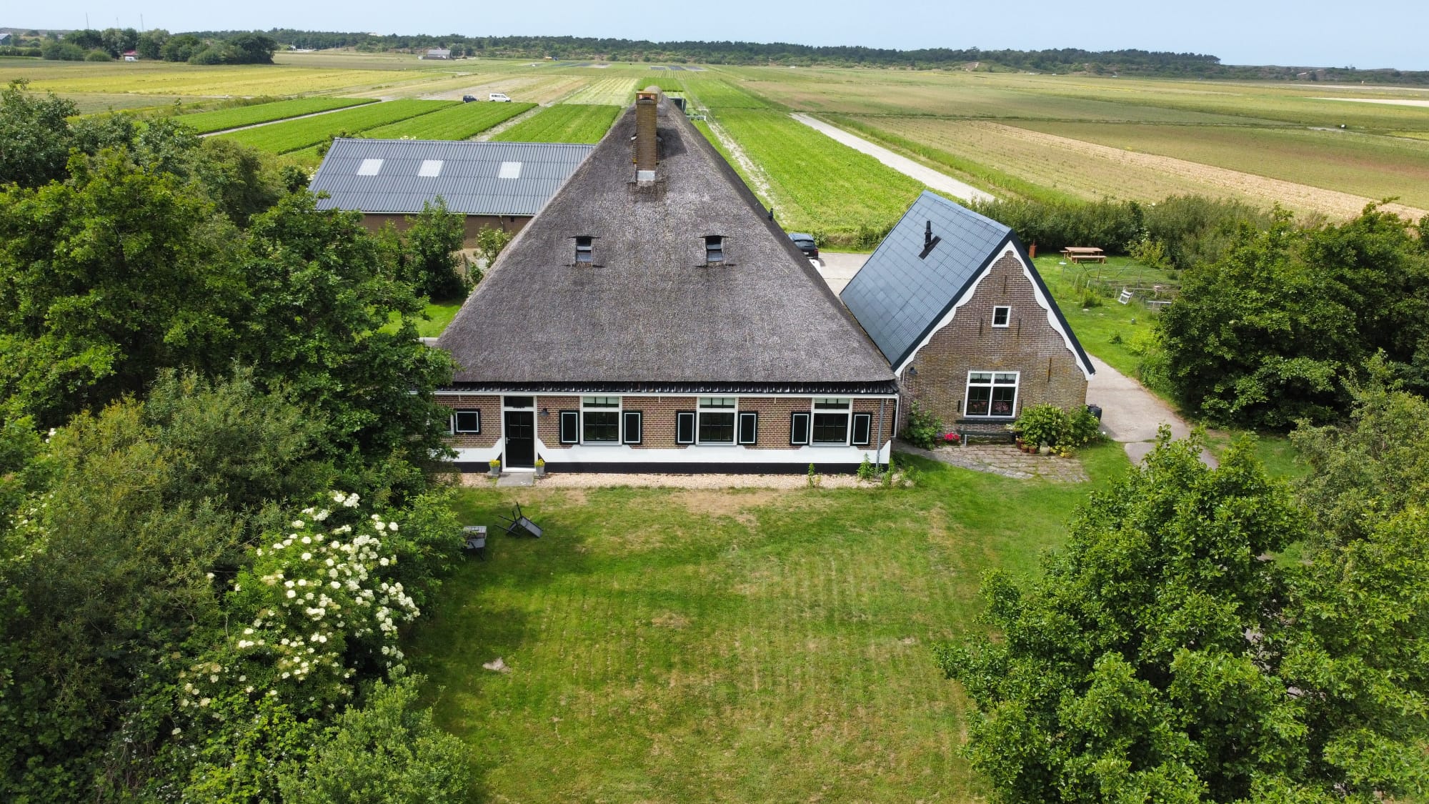 Luchtfoto van een boerderij met rieten dak in de polder