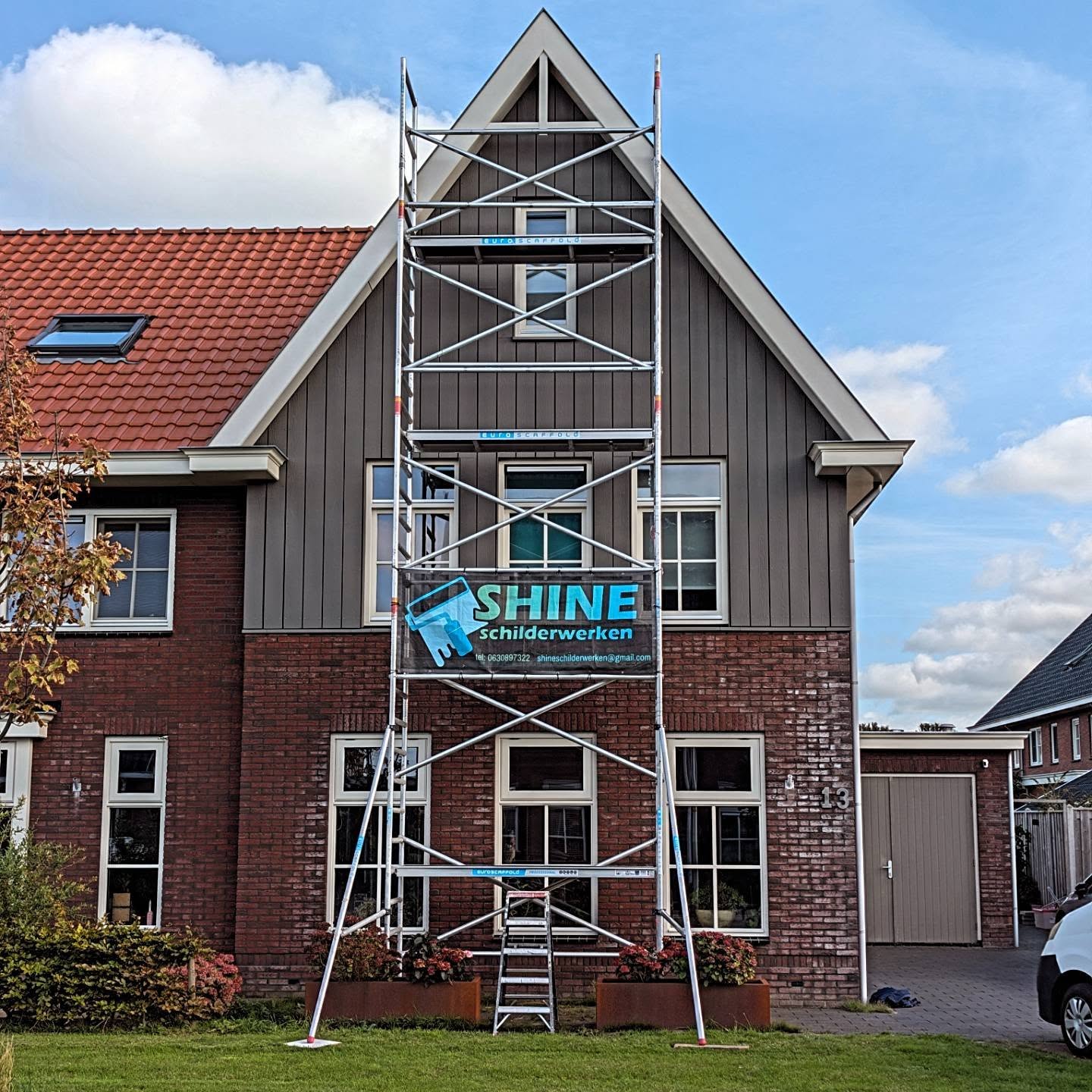 Woning met grijsgroene gevelbetimmering en een rolsteiger met het Shine spandoek