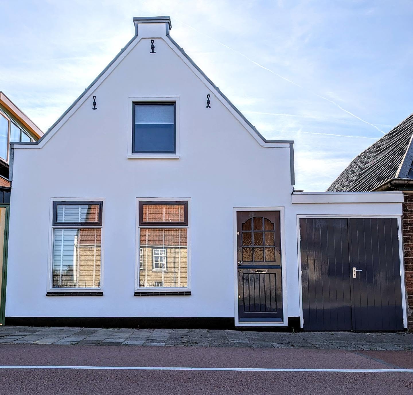 Wit geschilderde trapgevelwoning met zwarte deuren en kozijnen